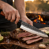 Cuchillo chef gyuto de acero martillado MenCity con mango de madera, cortando carne junto al asador - lifestyle en uso
