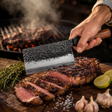 Hacha cleaver de acero martillado MenCity con mango de madera, cortando carne asada en tabla de nogal junto al asador - lifestyle en uso