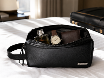 Necessaire Piel Negro abierto en cuarto de hotel con cologne reloj y cartera - viaje ejecutivo MenCity
